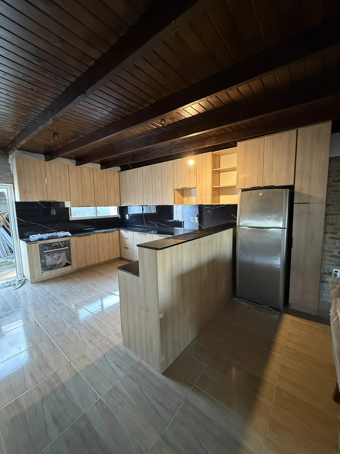 Cocina con península realizada por Alberto, con frentes en tono madera y mesadas negras, durante la instalación.