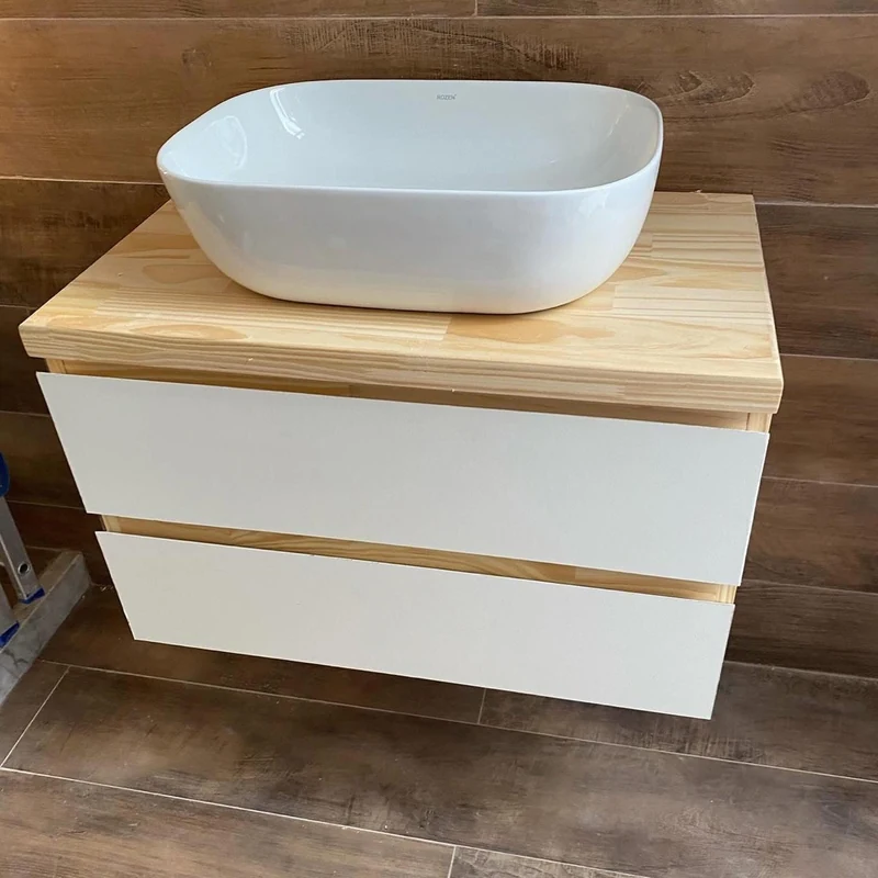 Mueble de baño realizado por Alberto Muebles a Medida, con cajones blancos y cubierta de madera.
